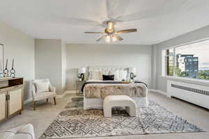 Bedroom featuring light carpet, radiator, and a ceiling fan