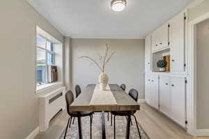 Dining area featuring radiator, light wood finished floors, and ornamental molding