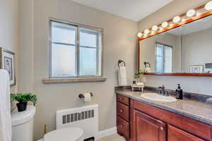 Half bath featuring radiator heating unit and vanity