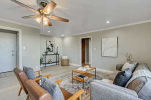 Living room with recessed lighting, ornamental molding, light wood-style flooring, and ceiling fan