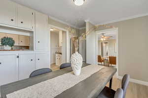 Dining room with light wood-style flooring, ornamental molding, and a ceiling fan