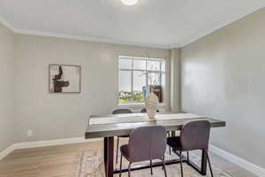 Dining area featuring ornamental molding and light wood-style floors