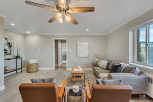 Living room featuring radiator heating unit, light wood-style flooring, ceiling fan, crown molding, and recessed lighting