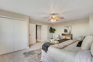 Bedroom featuring light carpet, a closet, and a ceiling fan