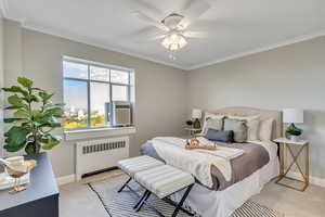 Bedroom with radiator, light carpet, ornamental molding, a ceiling fan, and cooling unit