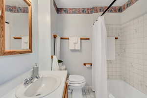Full bath featuring shower / bathtub combination with curtain, vanity, and tile patterned floors