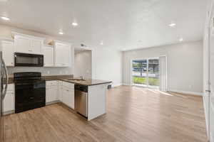 Kitchen with black appliances, white cabinetry, a peninsula, recessed lighting, and light wood-style flooring