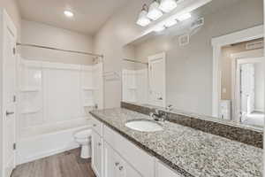 Full bath with shower / bathtub combination, vanity, and light wood-style flooring
