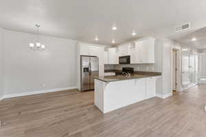 Kitchen with black appliances, white cabinets, decorative light fixtures, dark stone counters, and recessed lighting