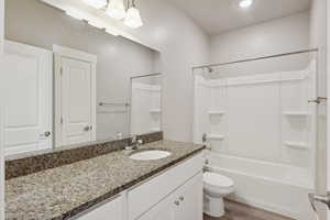 Bathroom with shower / tub combination, vanity, dark wood-style flooring, and recessed lighting