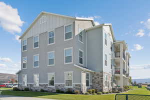 View of front facade with a front yard, stone siding, board and batten siding, and a mountain view