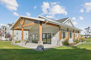 Back of property with a yard, board and batten siding, a patio, and a residential view