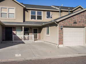 Traditional-style house featuring stucco siding, covered porch, brick siding, and roof with shingles