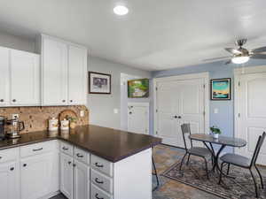 Kitchen featuring white cabinets, tasteful backsplash, a peninsula, and ceiling fan
