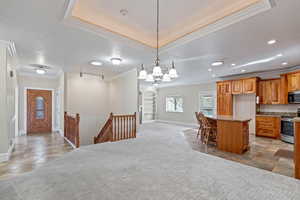 Kitchen featuring ornamental molding, light colored carpet, cherry cabinets, open floor plan, and appliances with stainless steel finishes