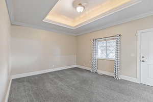 Primary bedroom with crown molding and a raised ceiling. Also has access to back yard.