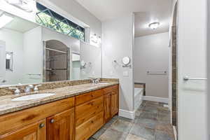 Primary bath with a tile shower, a textured ceiling, double vanity, and a garden tub