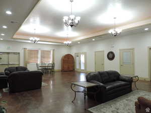 Gathering room with recessed lighting, a raised ceiling, concrete flooring, a fireplace, and crown molding