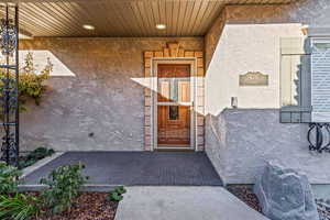 View of exterior entry featuring stucco siding and covered porch