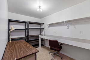 Office space with a textured ceiling and light carpet