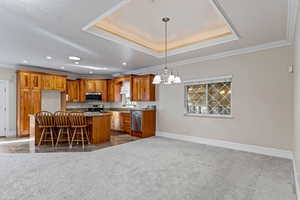 Kitchen featuring crown molding, cherry cabinets, open floor plan, a tray ceiling, and a center island