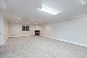 Basement with recessed lighting, fireplace, ornamental molding, and a textured ceiling