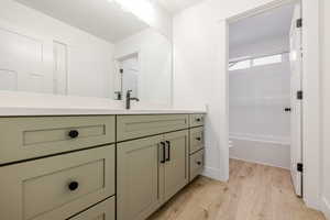 Bathroom with vanity, light wood finished floors, and bathtub / shower combination