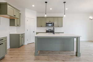 Kitchen with green cabinetry, light wood finished floors, and decorative light fixtures