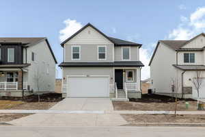 Traditional-style house with covered porch, concrete driveway, an attached garage, and roof with shingles