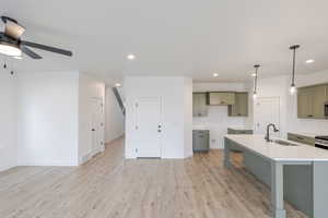 Kitchen with hanging light fixtures, gray cabinets, a kitchen breakfast bar, light wood finished floors, and ceiling fan