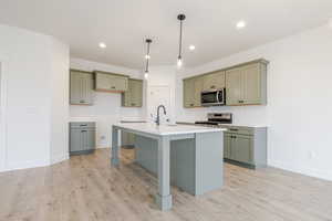 Kitchen featuring a breakfast bar, pendant lighting, stainless steel appliances, and light wood-style floors