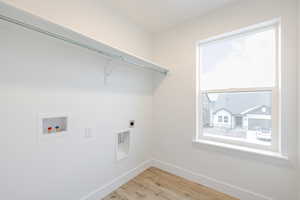 Laundry room with light wood-type flooring, hookup for an electric dryer, and washer hookup