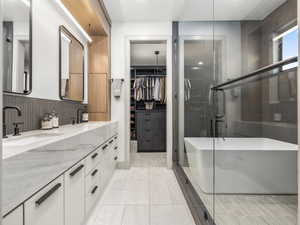 Full bathroom with double vanity, a stall shower, light tile patterned floors, and a walk in closet