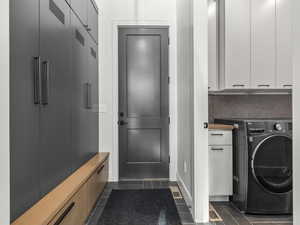 Laundry area featuring washer / clothes dryer, cabinet space, and dark tile patterned floors