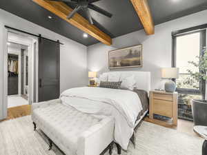 Bedroom featuring beamed ceiling, a barn door, recessed lighting, ceiling fan, and wood finished floors