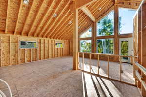 Unfurnished living room with high vaulted ceiling and a wall mounted AC