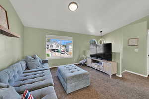 Carpeted living room featuring baseboards and lofted ceiling
