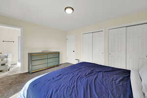 Bedroom featuring carpet, two closets, and ensuite bath
