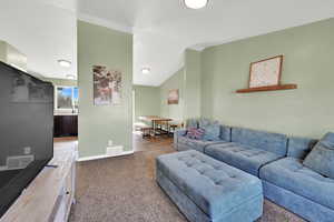 Carpeted living area featuring vaulted ceiling and baseboards