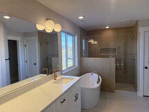 Full bath featuring a freestanding bath, a stall shower, vanity, recessed lighting, and light tile patterned floors