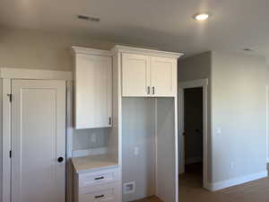 Kitchen with white cabinetry, light stone counters, and light wood finished floors