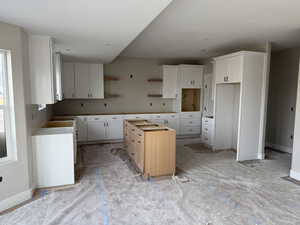 Kitchen with white cabinets, open shelves, and a center island