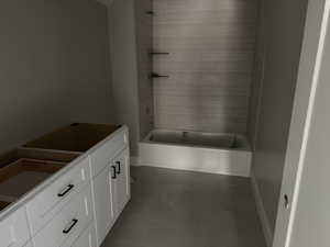 Bathroom with tub / shower combination, dark tile patterned floors, and vanity