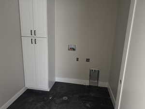 Washroom featuring cabinet space, hookup for a washing machine, and dark tile patterned flooring