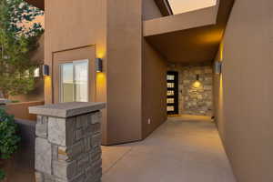 Entrance to property featuring stone siding, a patio, and stucco siding