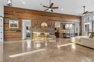 Living area with wooden walls, finished concrete floors, recessed lighting, and ceiling fan