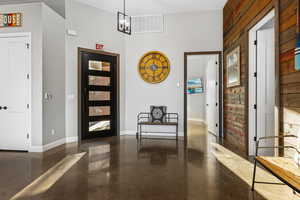 Foyer with finished concrete floors and wood walls