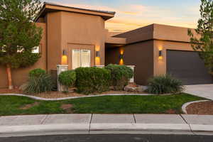 View of front of house with an attached garage, driveway, and stucco siding