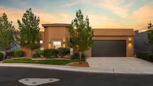 View of front of house with driveway, stucco siding, and a garage