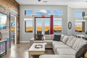 Living area featuring concrete flooring, plenty of natural light, wood walls, and a towering ceiling